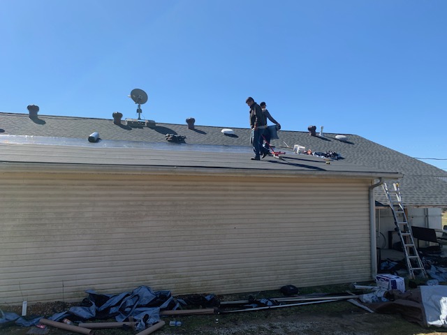 Before: crew stripping worn shingles off the roof during tear-off