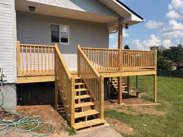 Close view of the new deck stairs, posts and spindle railing beside gray siding