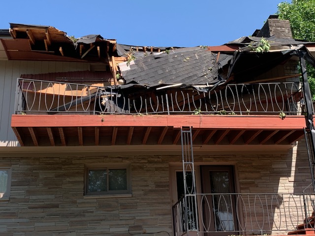 Before: collapsed shingle roof and broken framing above a second-story balcony