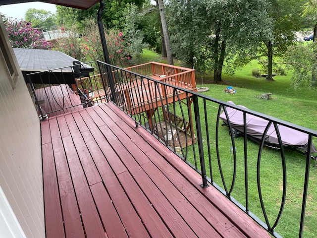 After: finished covered deck with new decking and iron railing