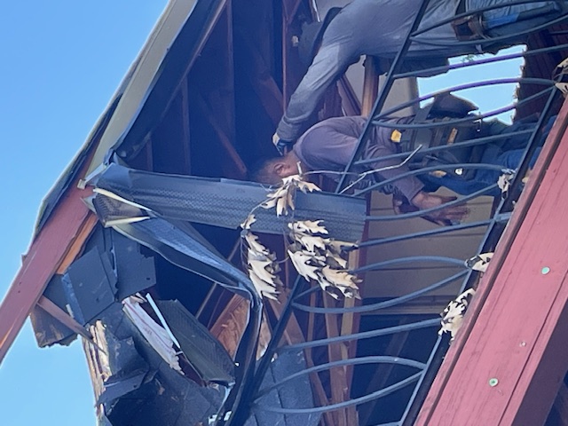 Before: crew tearing out damaged roof framing above a second-story deck